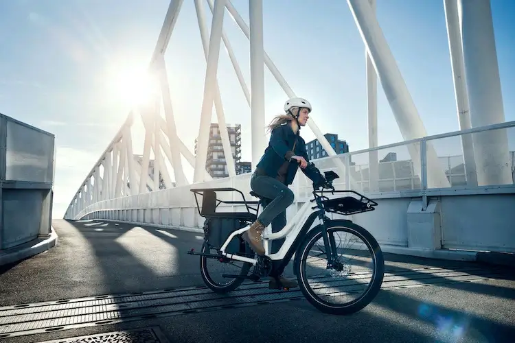 A woman crosses the bridge with the longtail electric bike